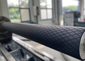 A technician performing a dynamic balancing test on a high-speed carbon fiber rubber covered roller to prevent vibration